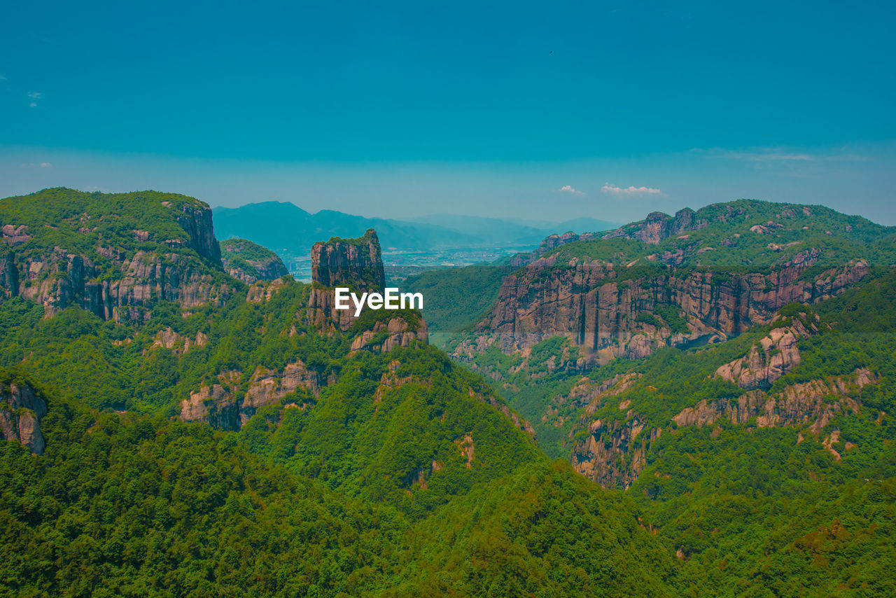 Scenic view of trees and mountains against blue sky