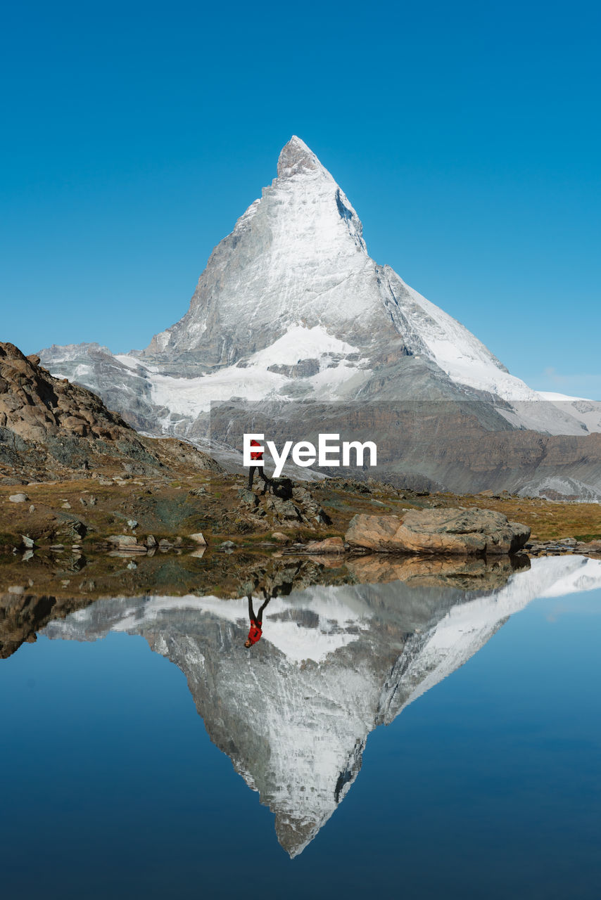 Reflection of man on lake against sky