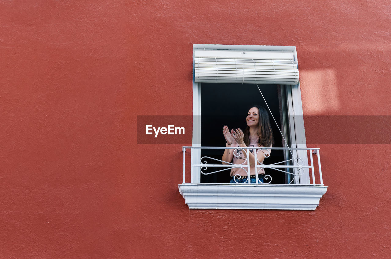 Woman clapping in the window of her house red