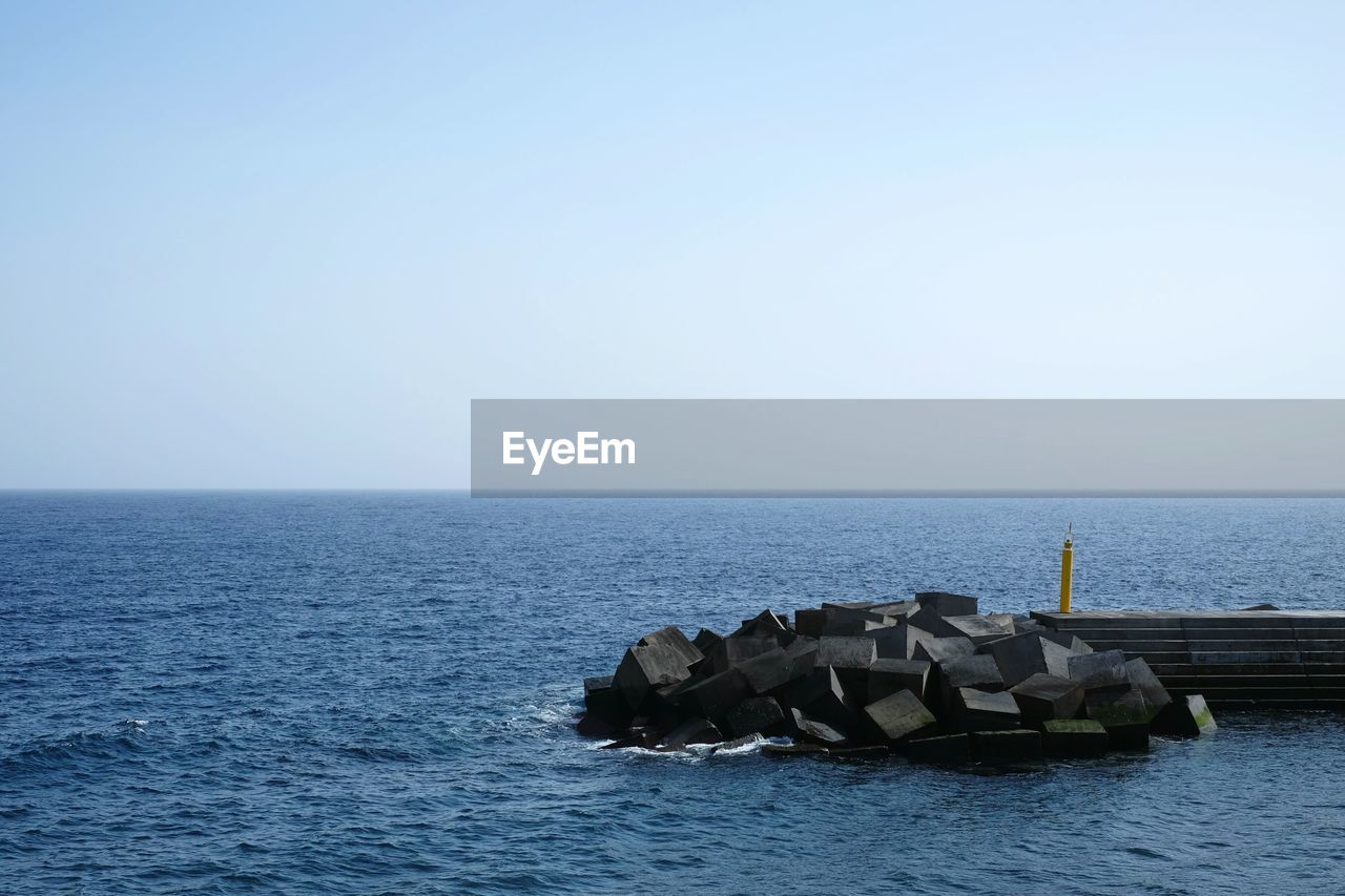 Groyne in sea against clear sky