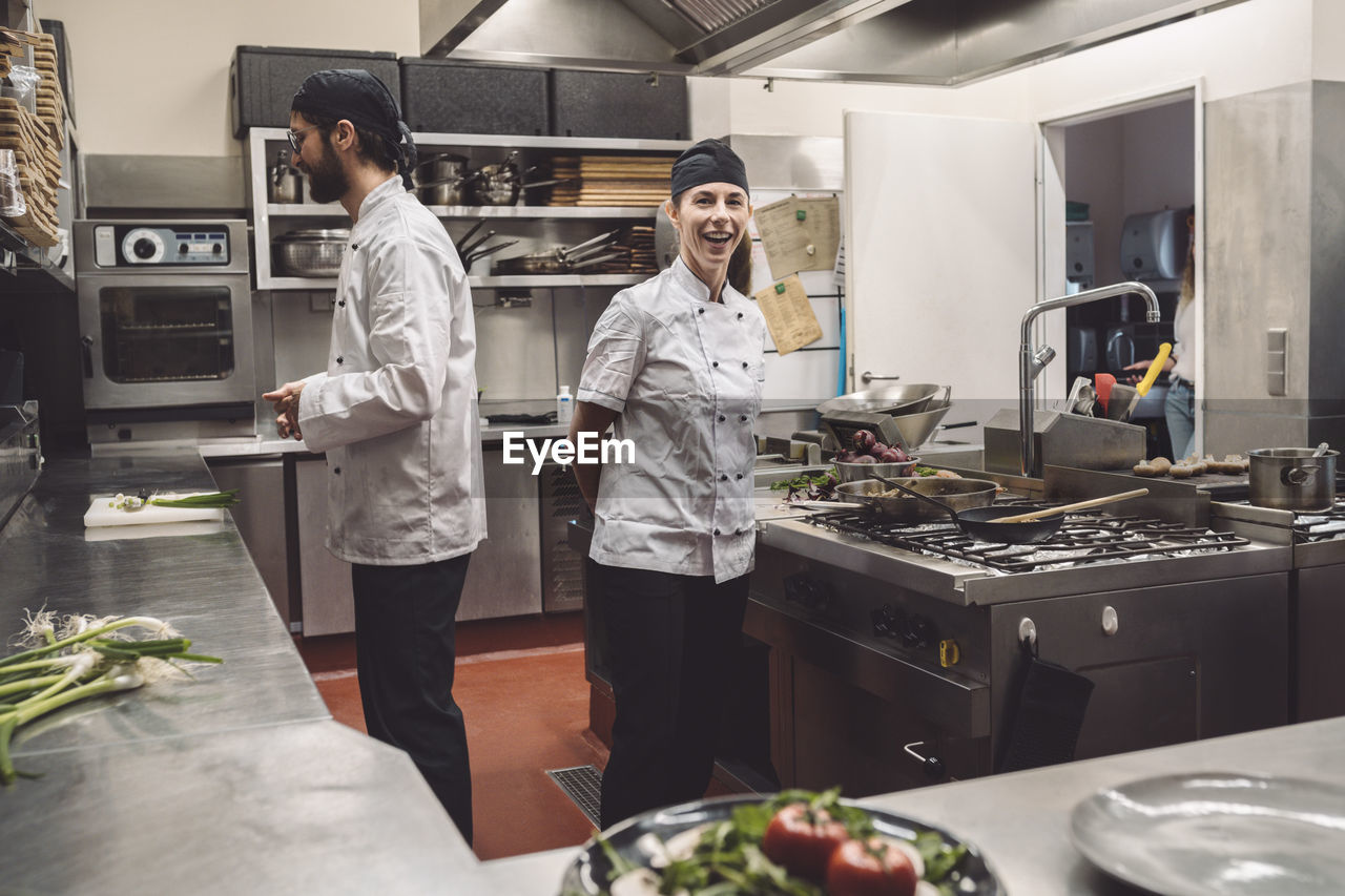 Portrait of smiling chef with coworker in kitchen restaurant