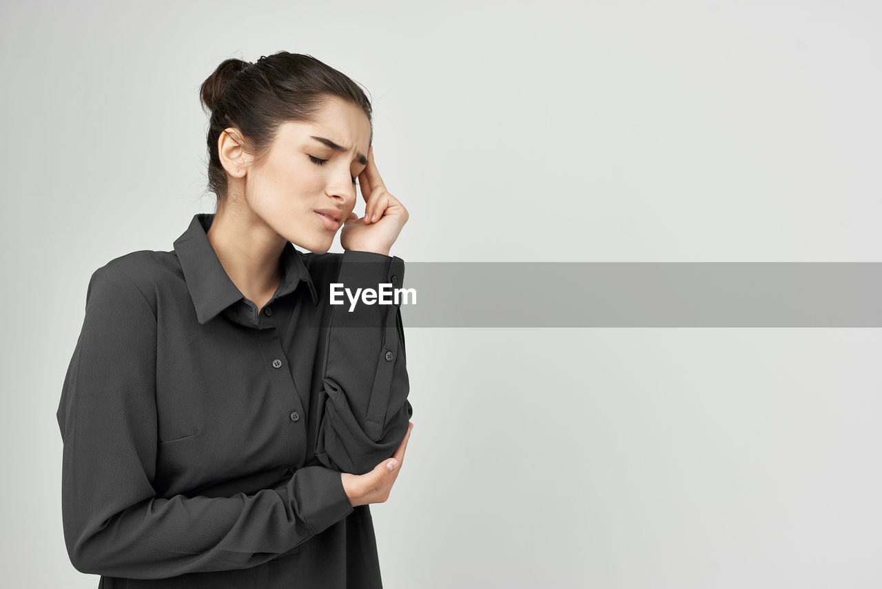 Young woman looking away while standing against white background