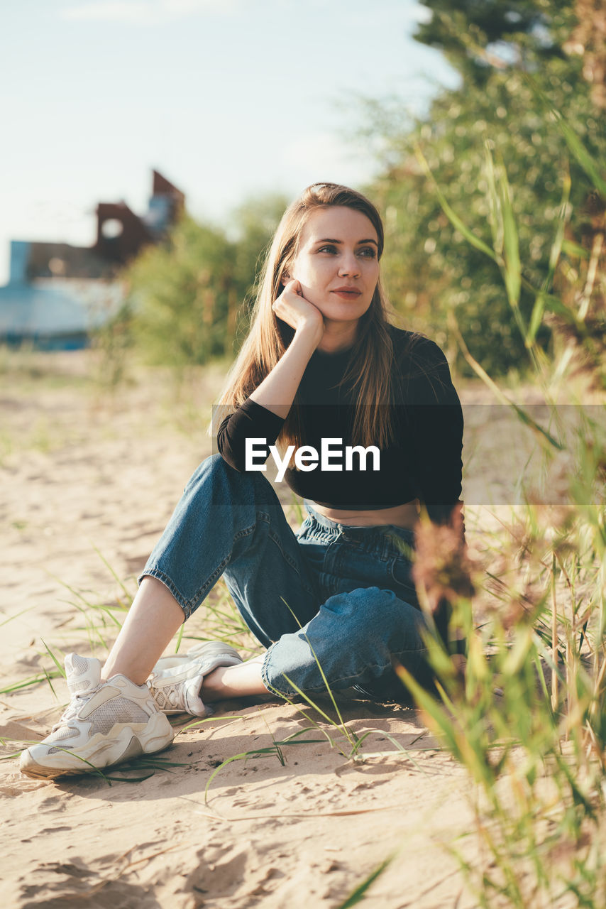 Beautiful woman sitting on land looking away