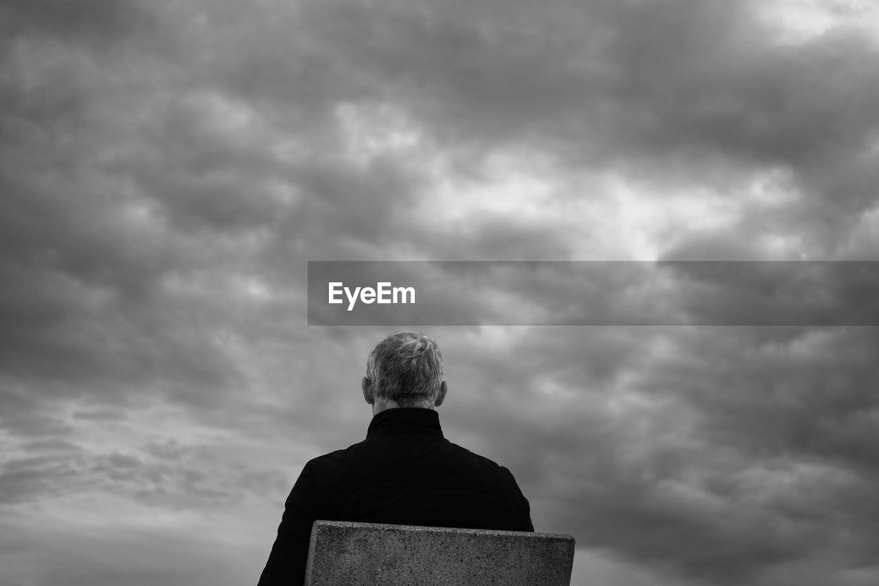 LOW ANGLE VIEW OF A MAN SITTING ON TOP OF SKY