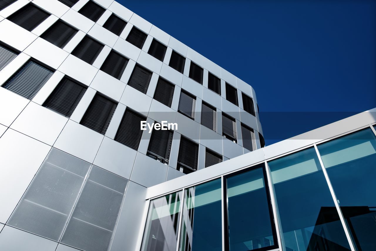 Low angle view of modern building against clear blue sky