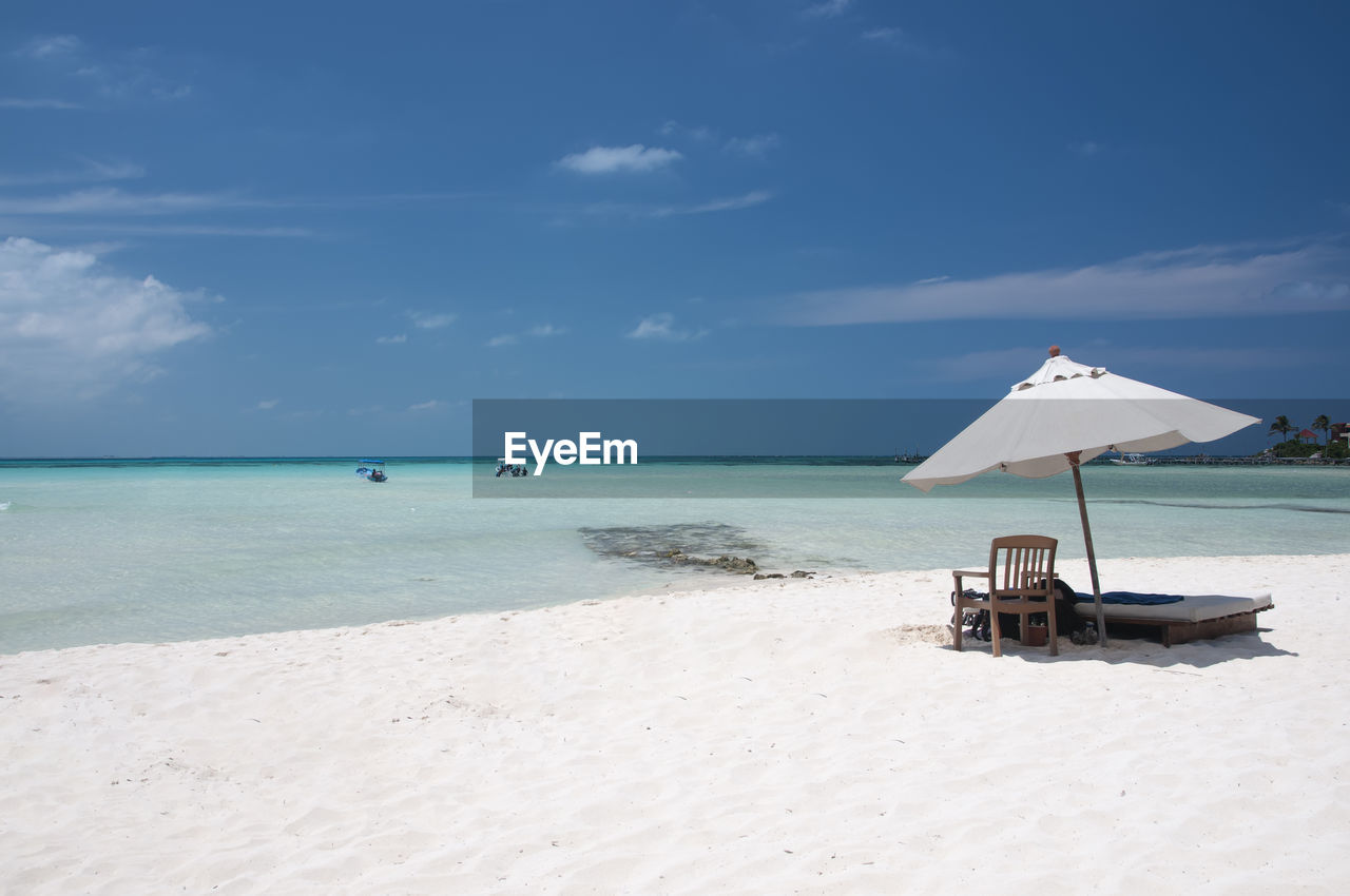 A sunny summer morning on the beautiful white sand beach with a chaise lounge and umbrella 