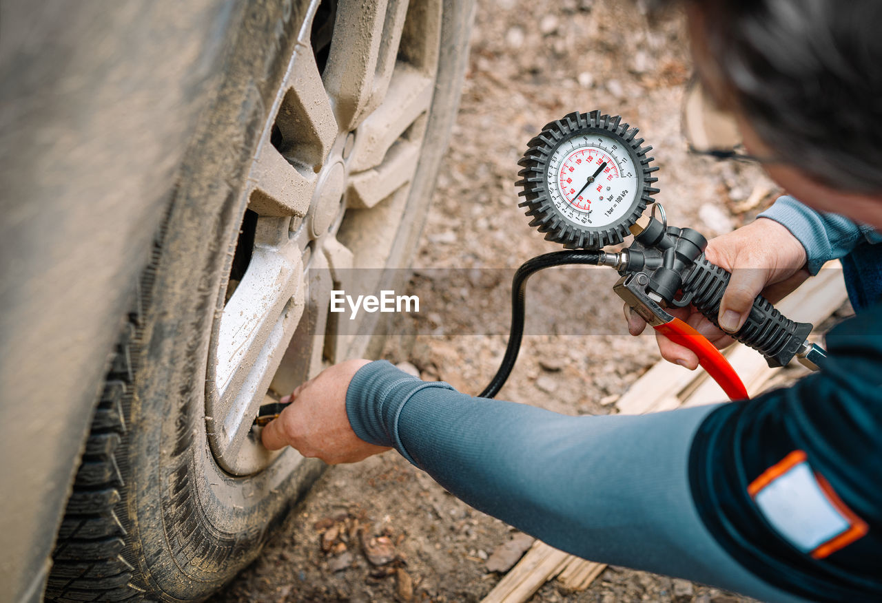 Person checking tire pressure with gauge instrument