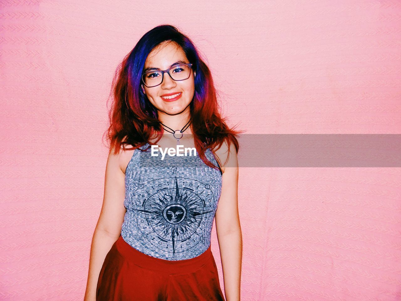 Portrait of smiling young woman standing against wall