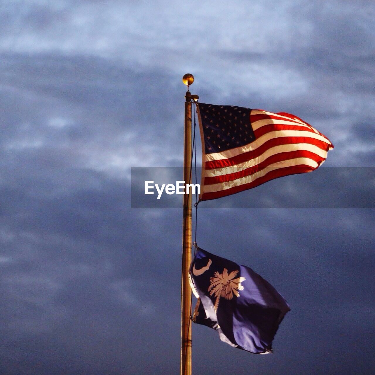 Low angle view of american flag against cloudy sky at dusk