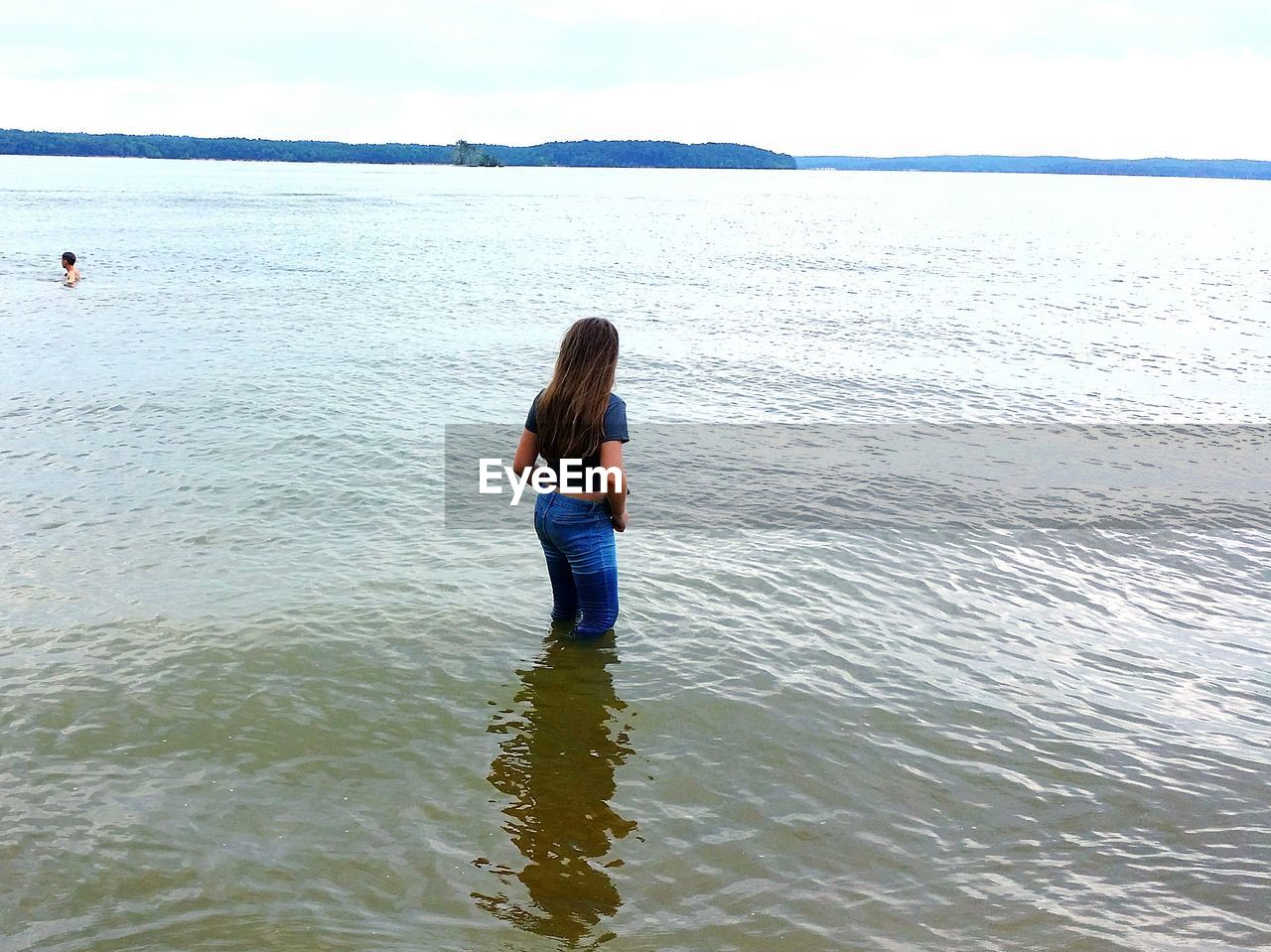 Rear view of woman standing in water at beach