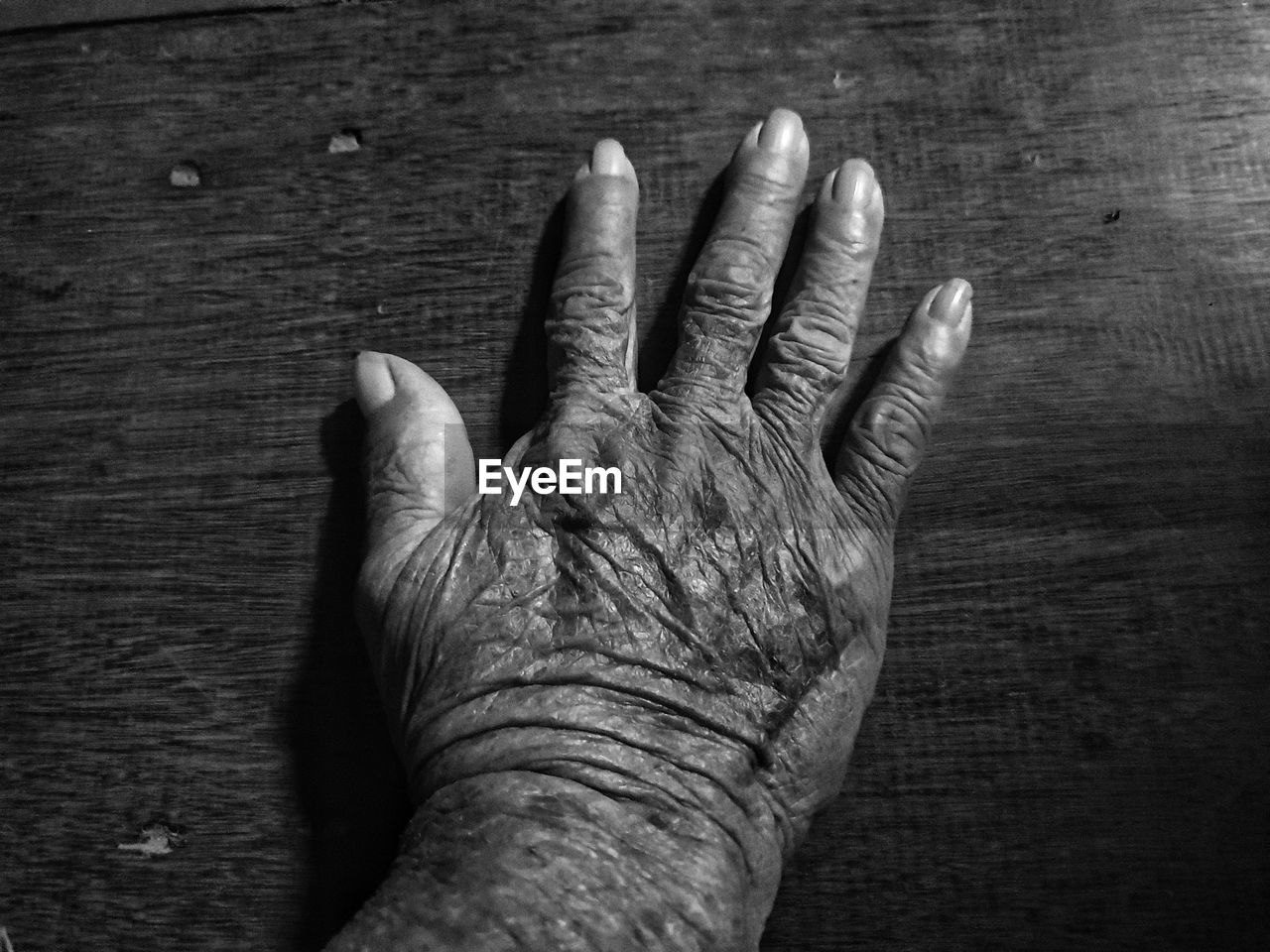 CLOSE-UP OF HUMAN HAND ON WOOD