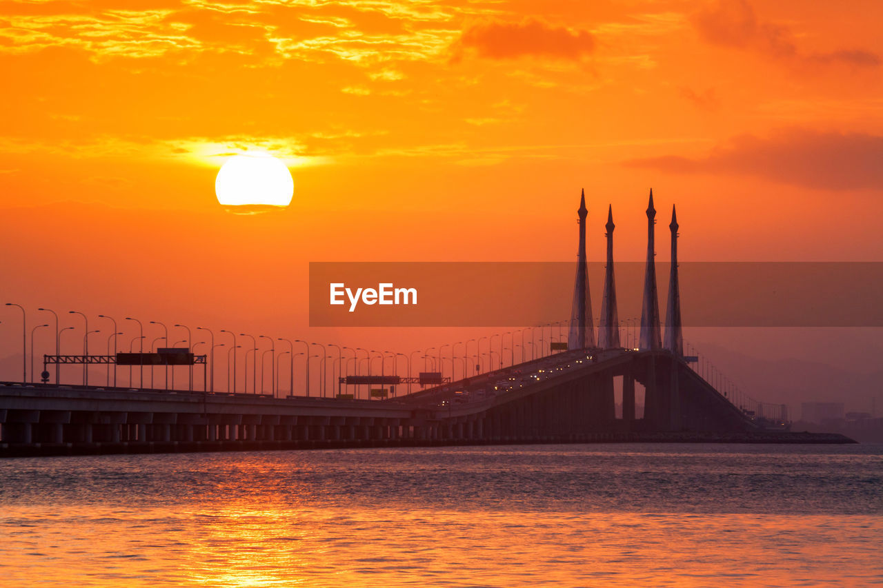 View of suspension bridge over river during sunset