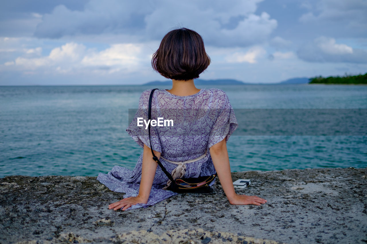 Rear view of woman sitting on sea shore