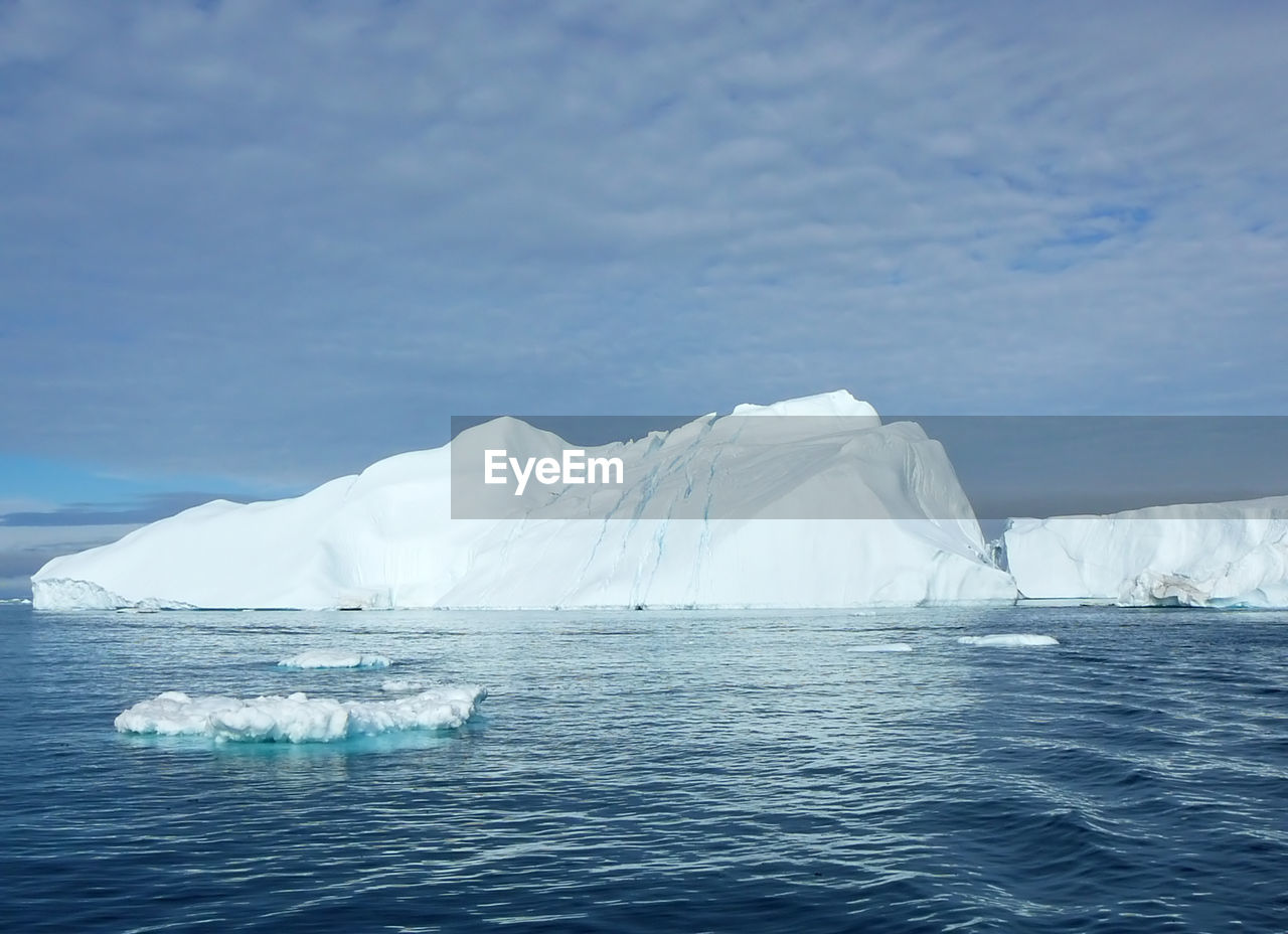 Scenic view of glacier by sea against sky