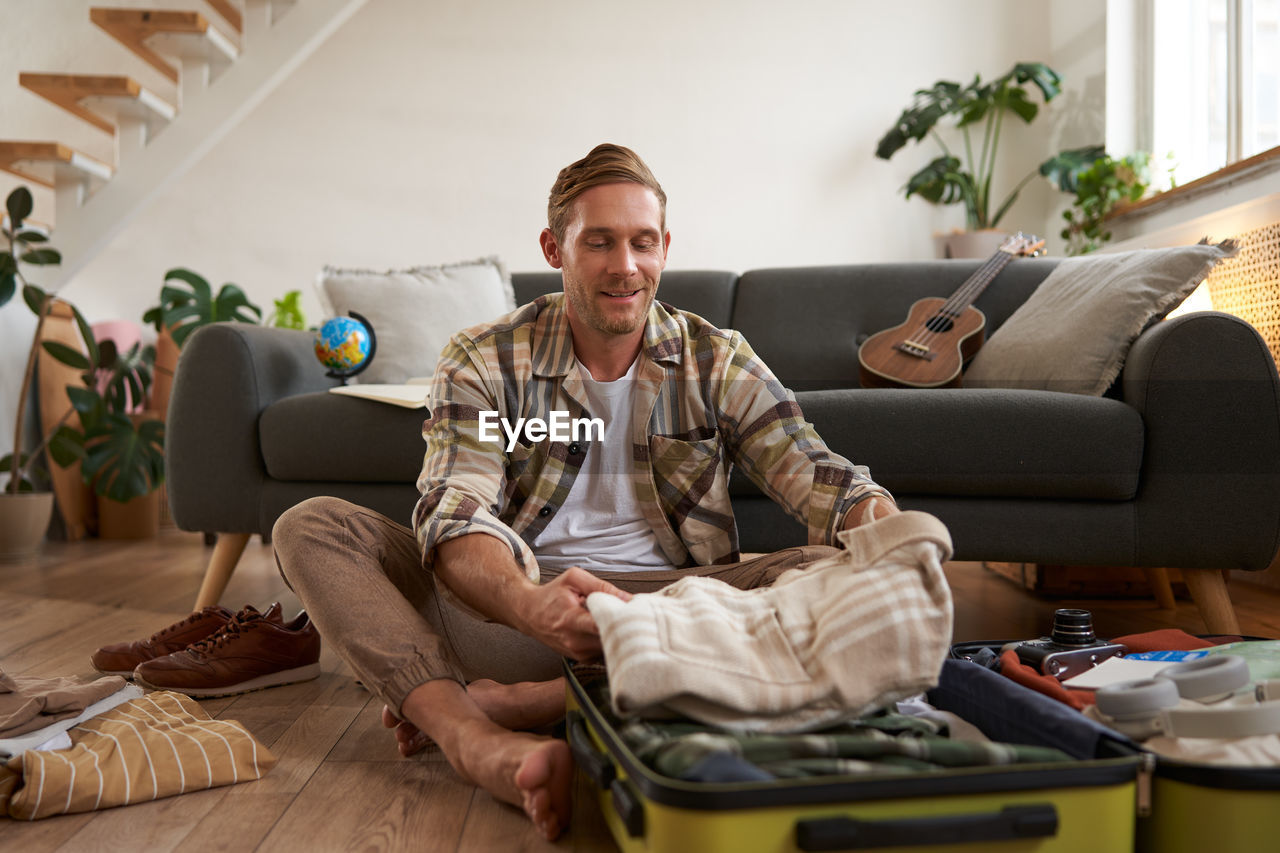 portrait of senior man using mobile phone while sitting on sofa at home