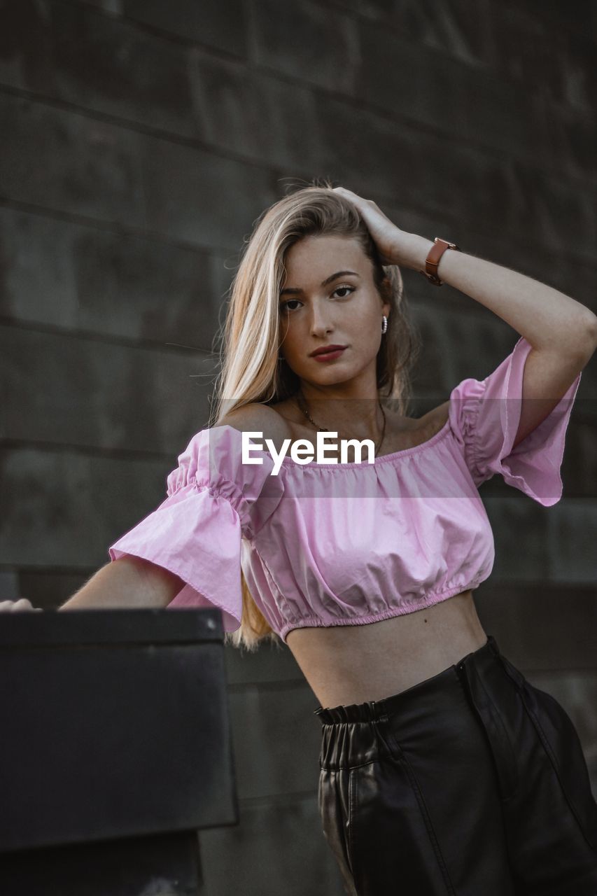 Portrait of beautiful young woman standing against wall