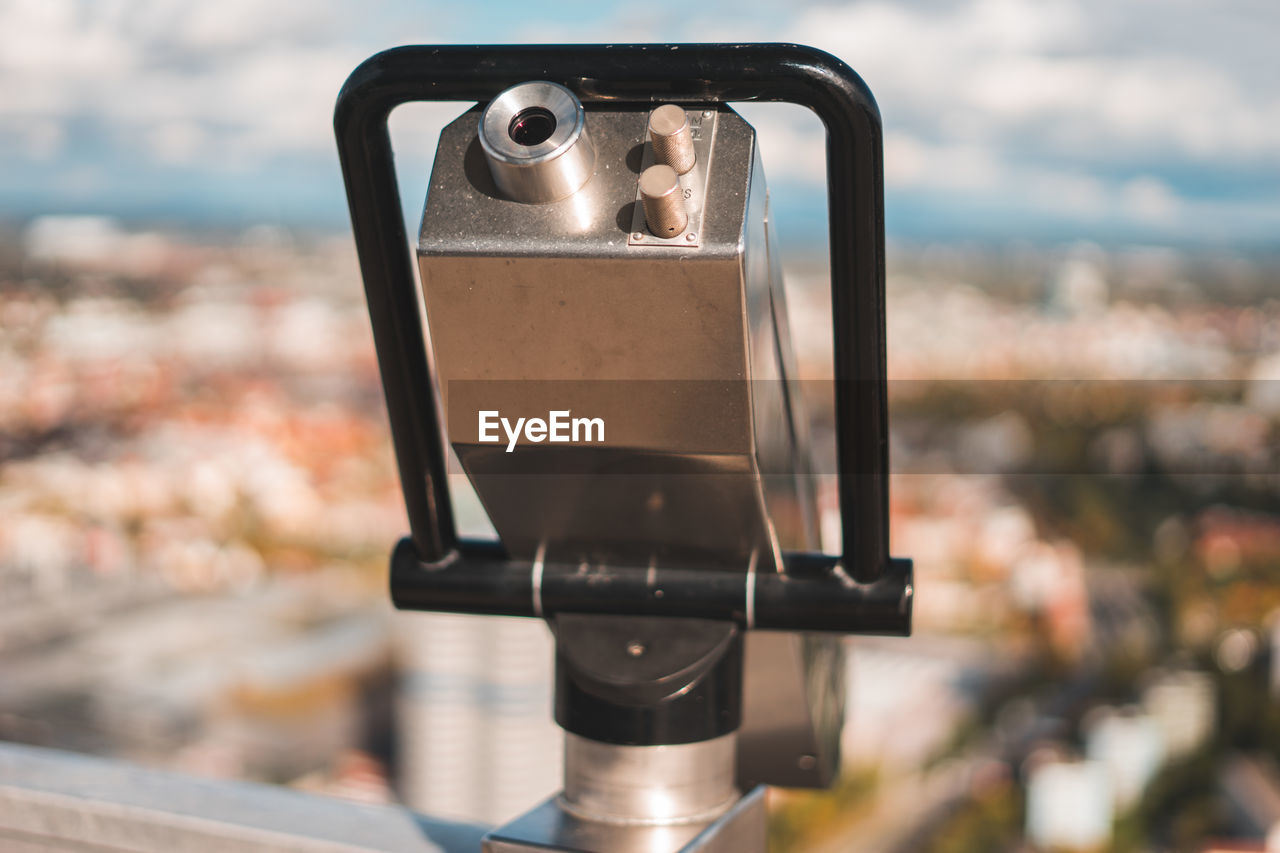 Close-up of coin-operated binoculars against cityscape