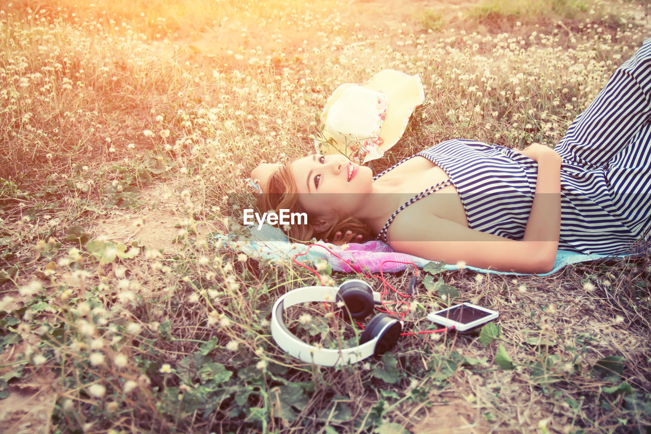 Woman with personal accessory lying down on field