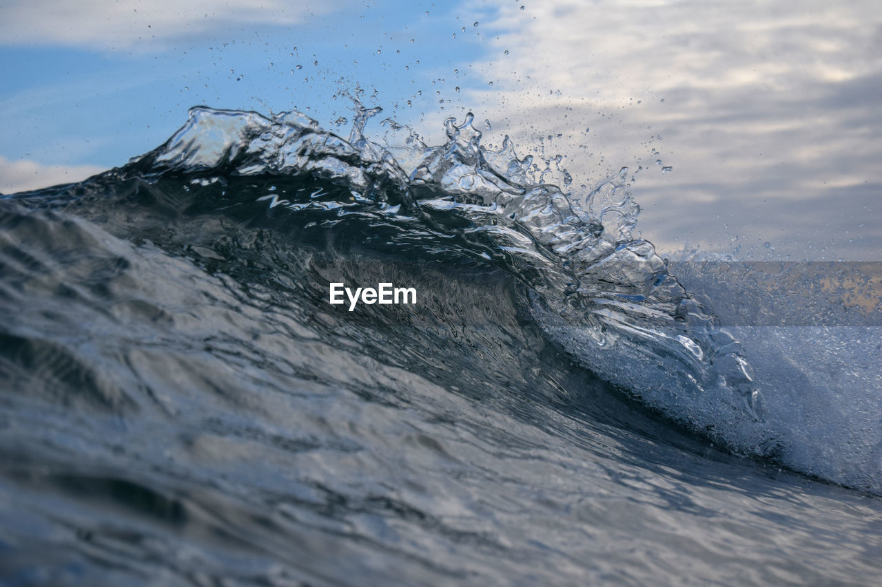 Waves splashing in sea against sky