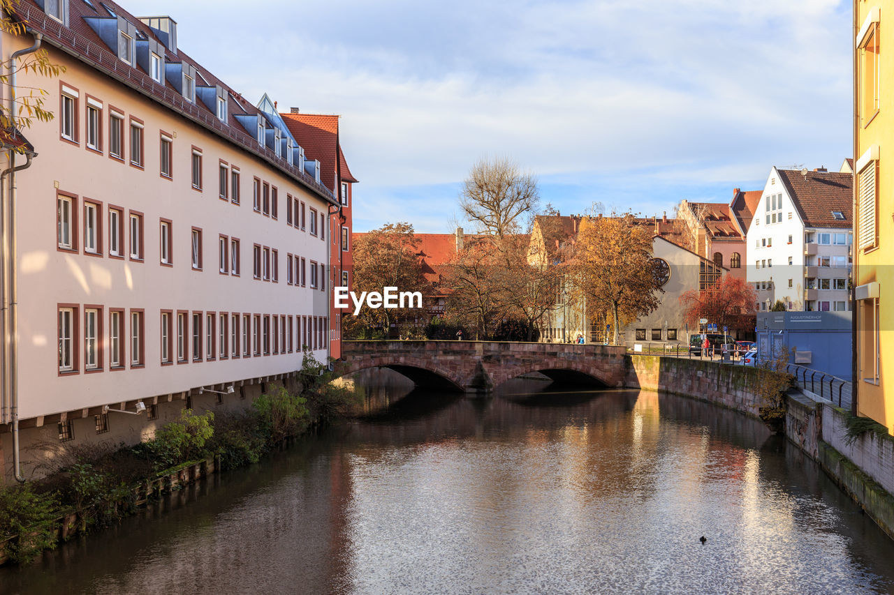 Canal in city against sky