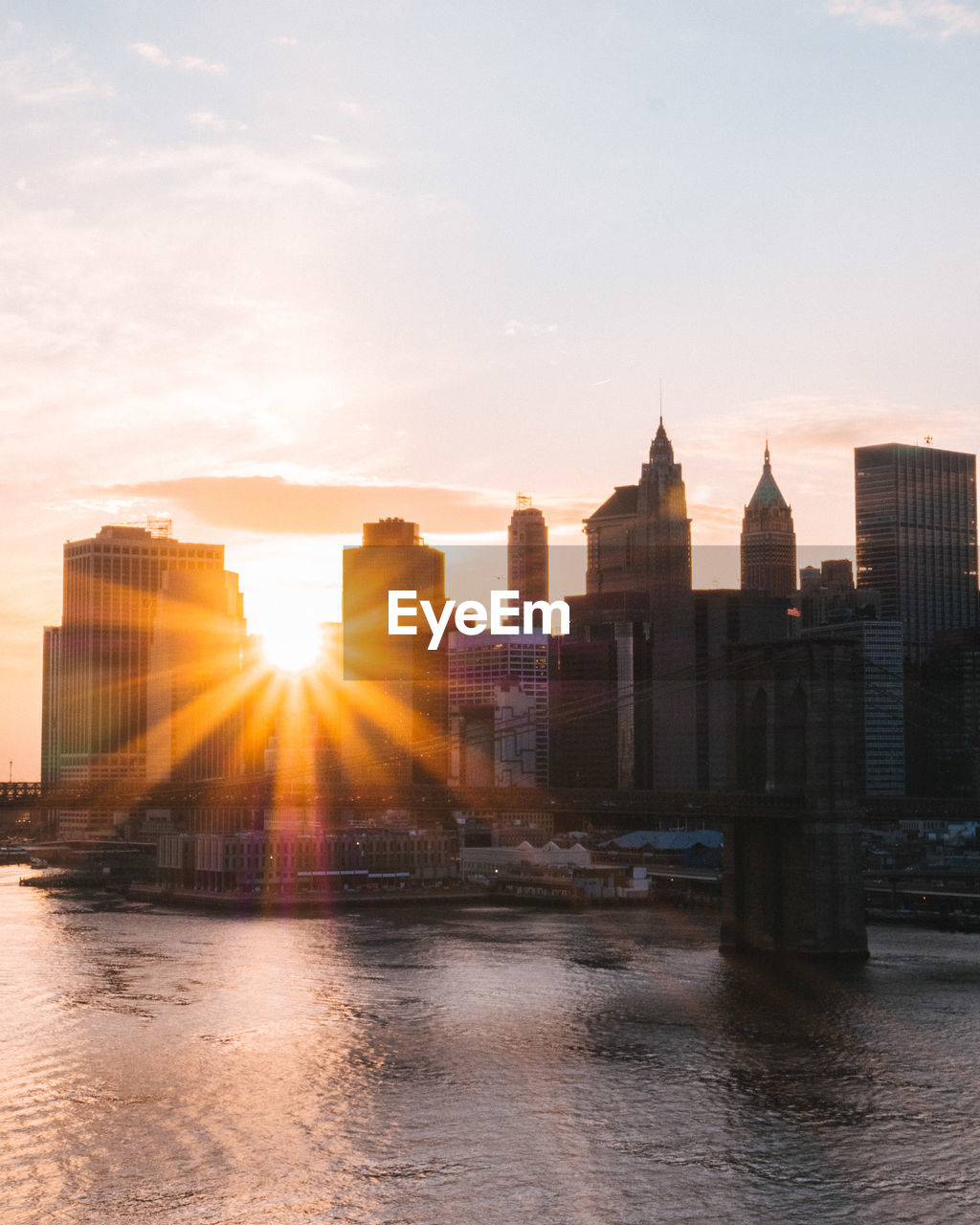 River in city against sky during sunset