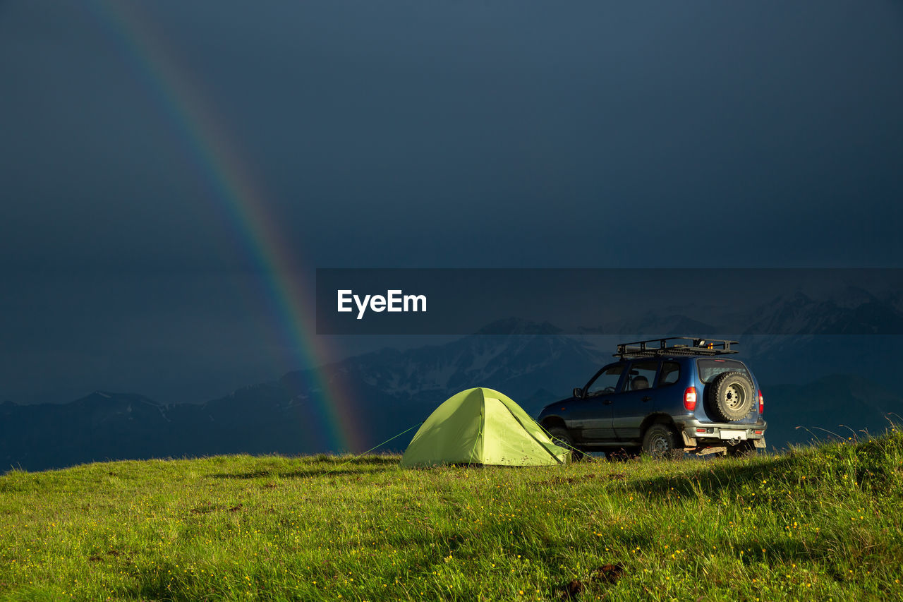Travel to the mountains by car with a tent. rainbow after rain