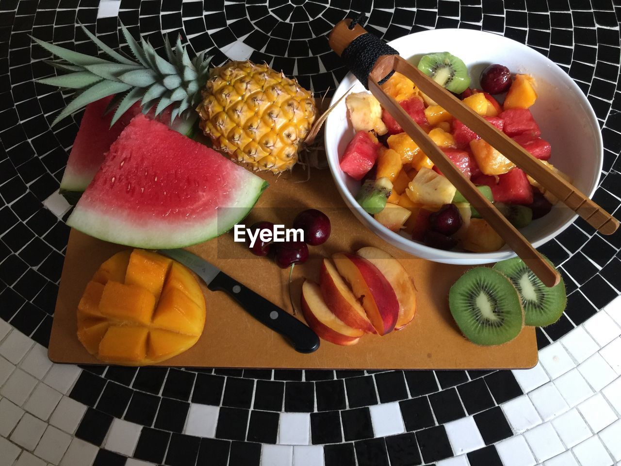 High angle view of chopped fruits with cutting board and serving tongs on floor