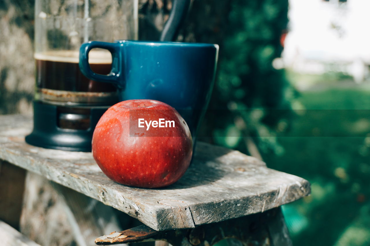 Close-up of apple and mug on table