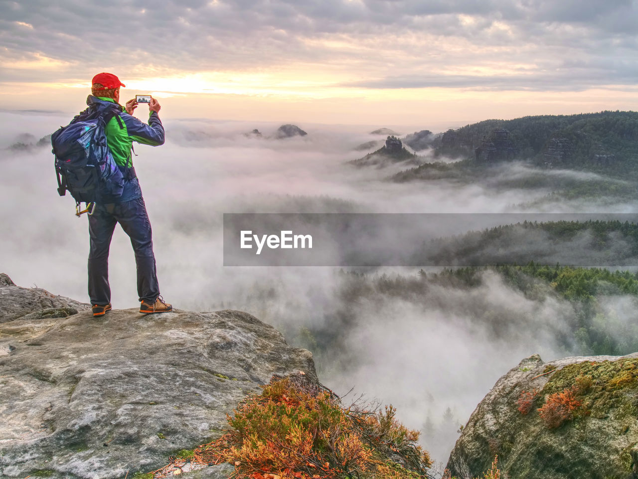 Fall nature within misty morning. photographer taking picture of forest, sky and clouds