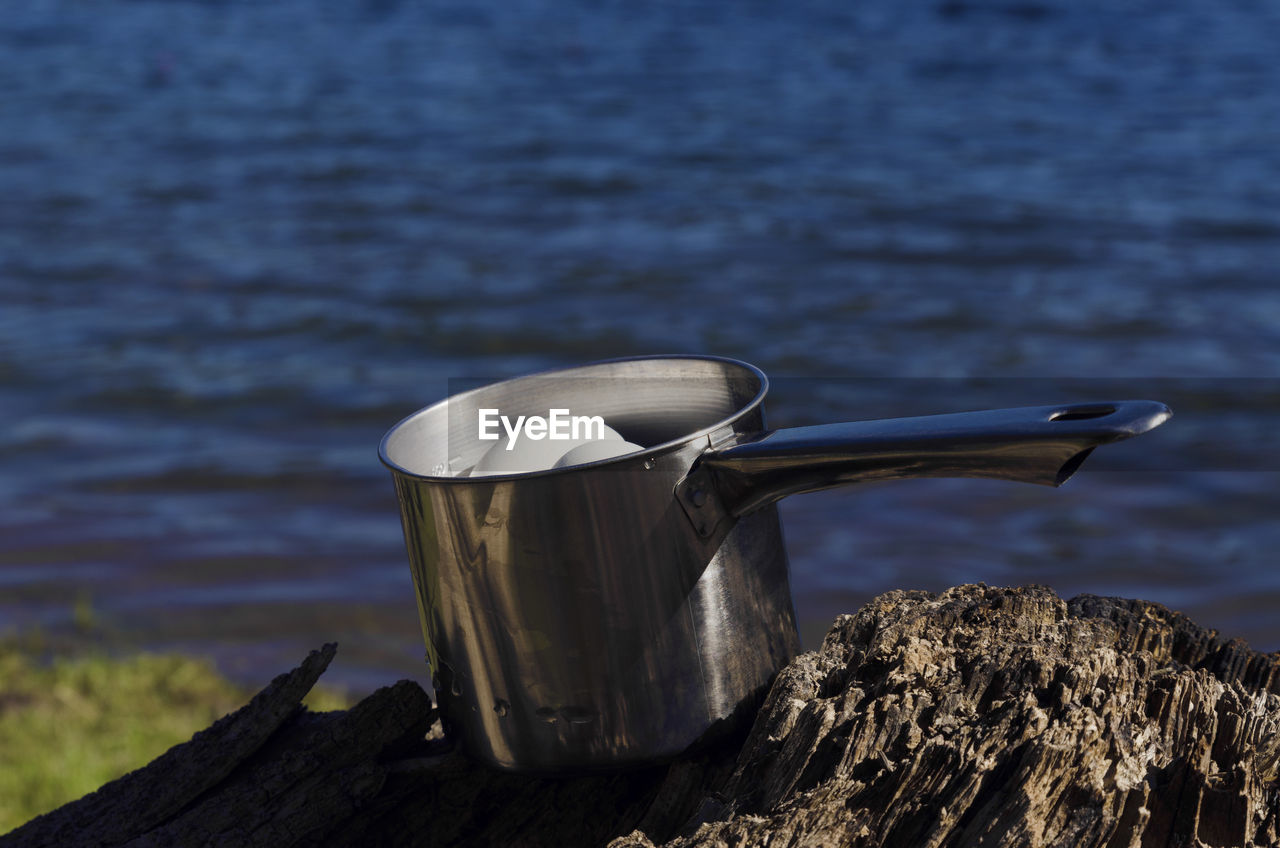 Eggs in utensil on wood by lake