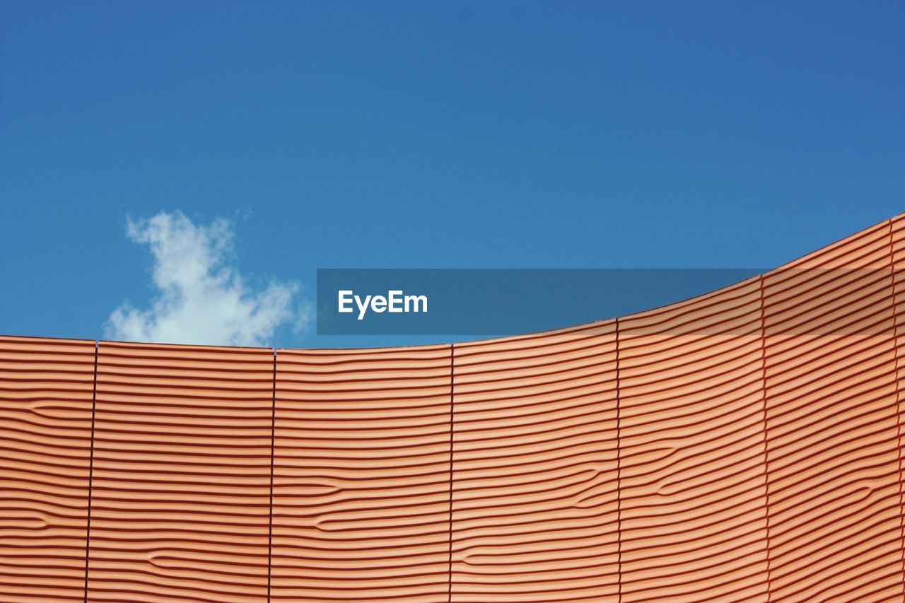 Low angle view of patterned wall against blue sky