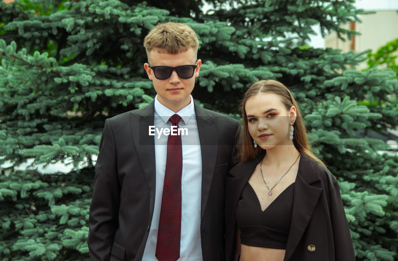 portrait of smiling couple standing against trees