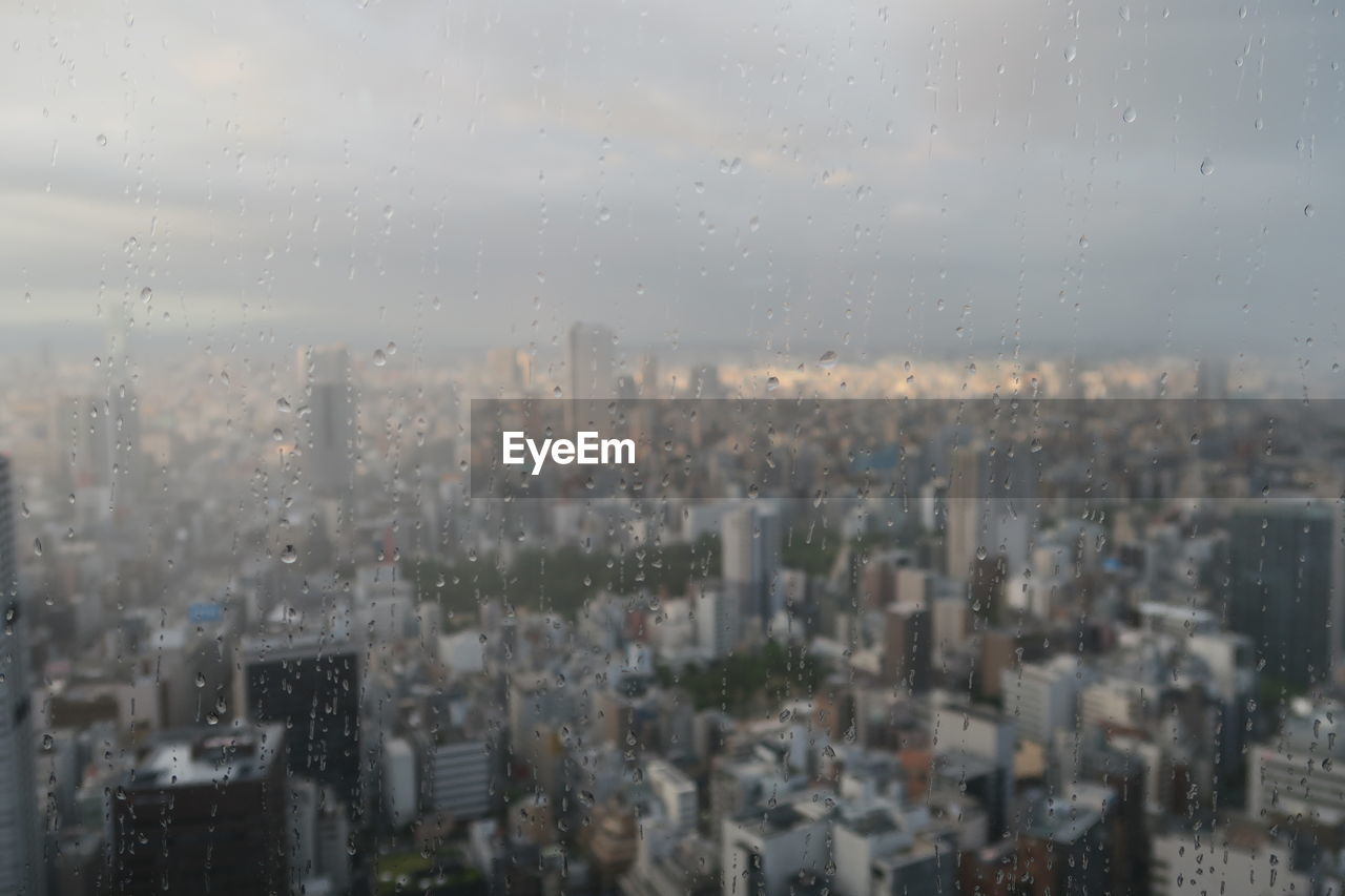 Aerial view of city buildings seen through wet glass window