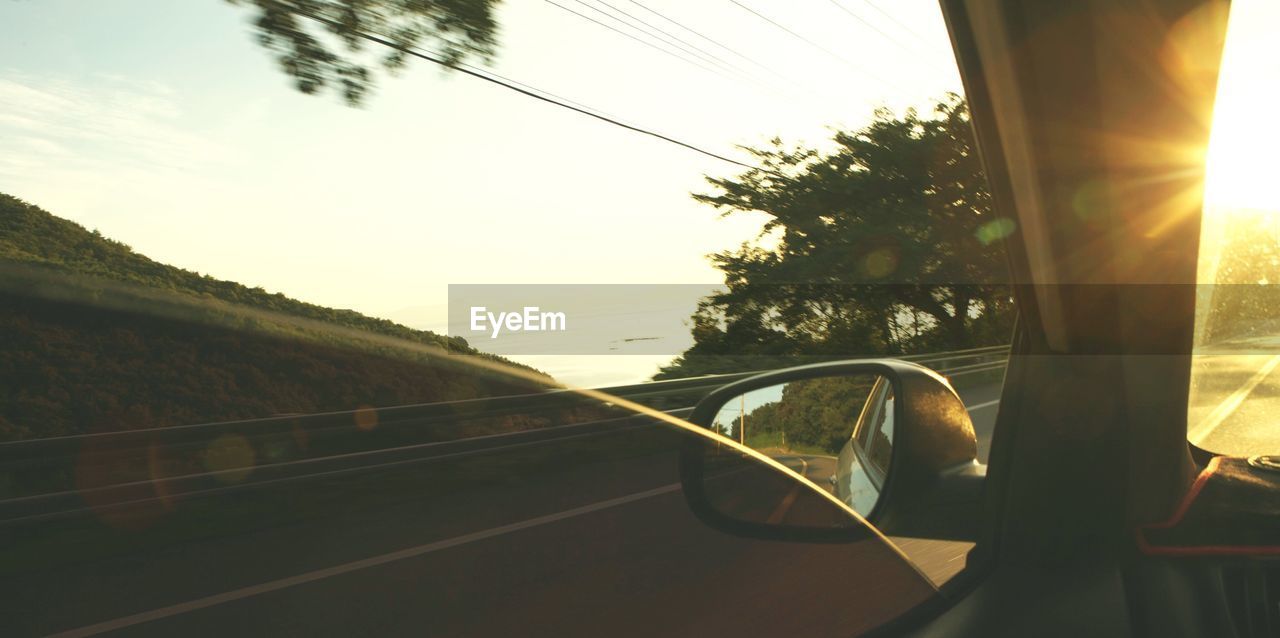 transportation, mode of transportation, car, glass - material, vehicle interior, motor vehicle, sky, nature, sunlight, land vehicle, tree, car interior, transparent, plant, sunset, window, road, no people, indoors, sun, electricity, lens flare