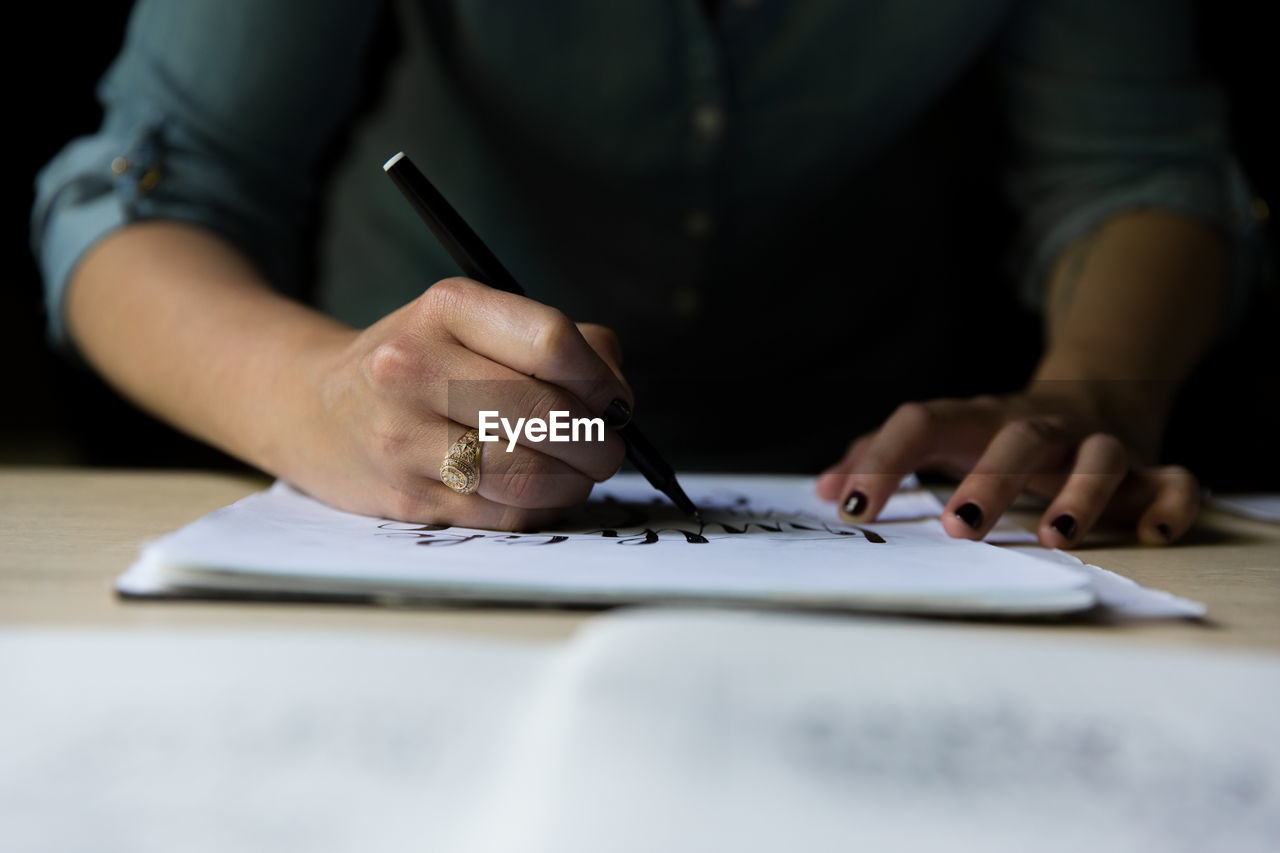 Cropped image of woman drawing on paper at table