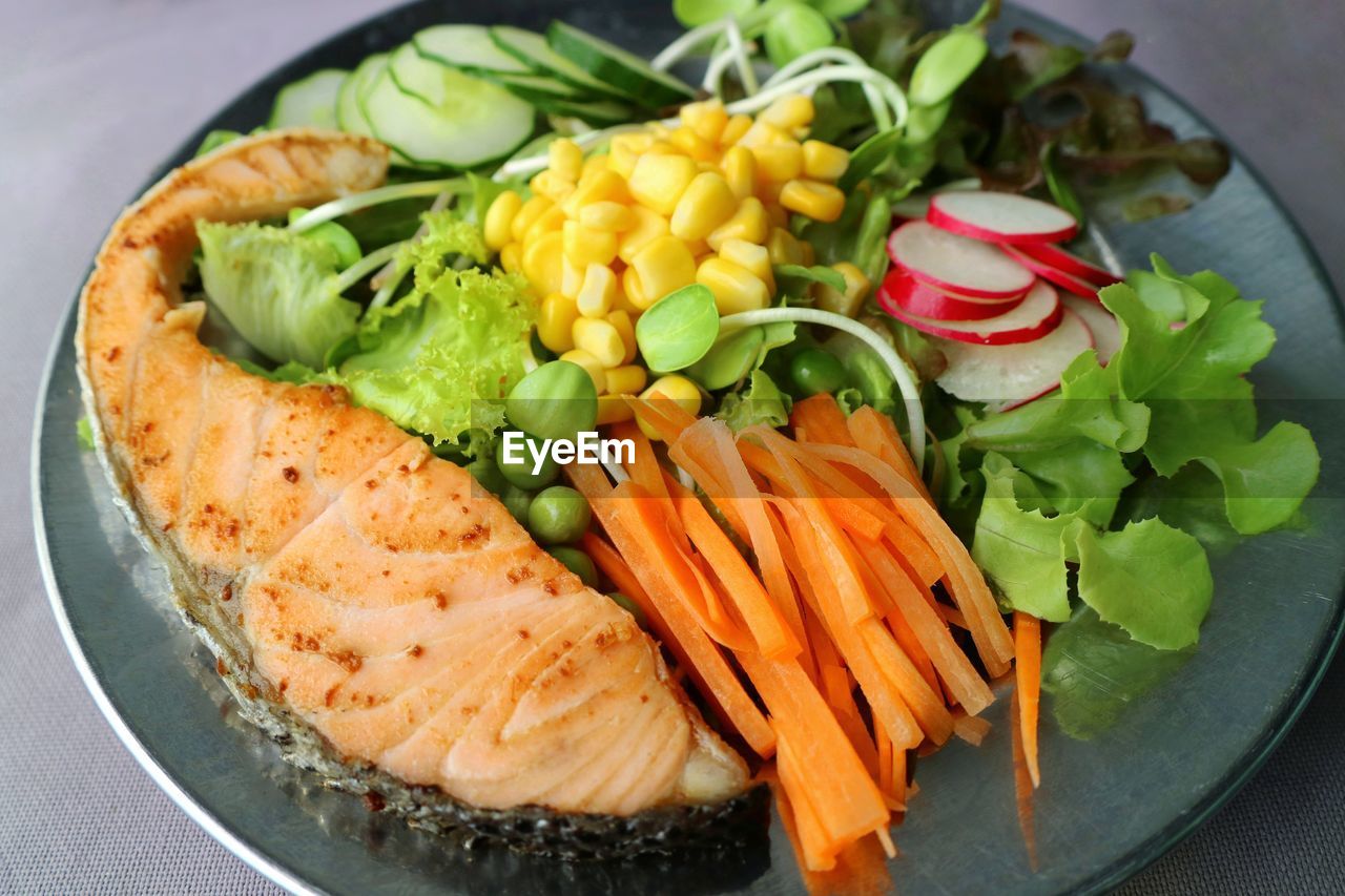 High angle view of salad served in plate with salmon grill.