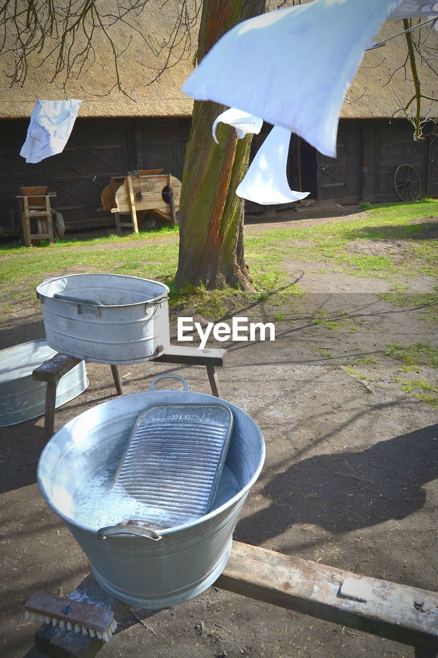 Buckets on field by clothesline against barn