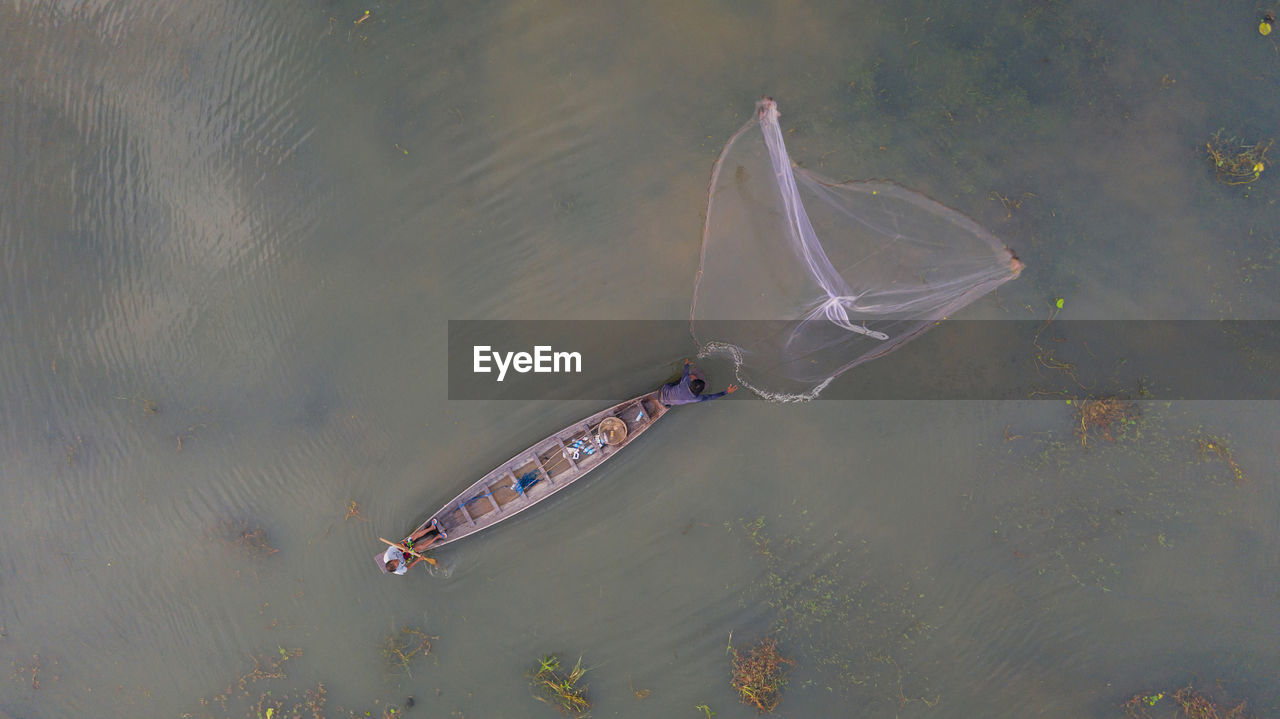 High angle view of fisherman throwing net at river