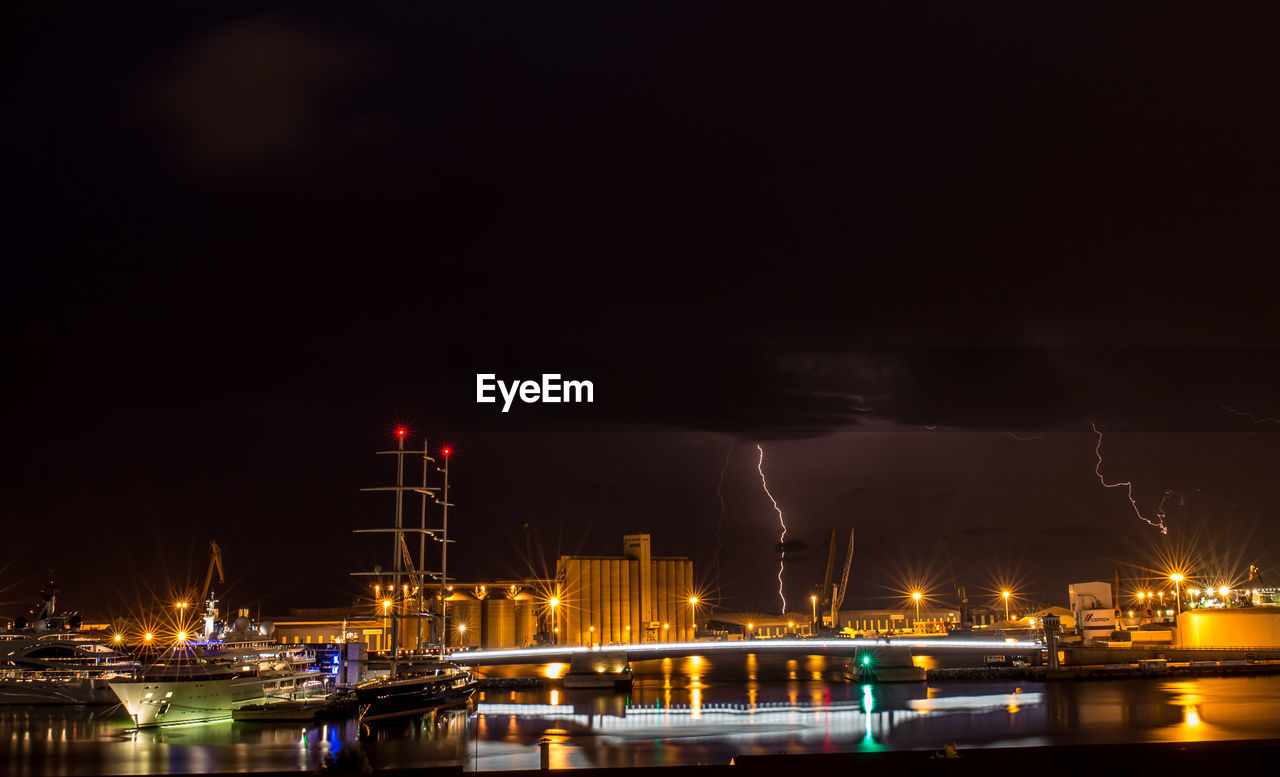 Illuminated harbor against sky at night