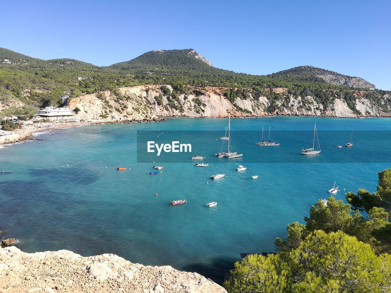 HIGH ANGLE VIEW OF BOATS MOORED ON SEA AGAINST CLEAR SKY