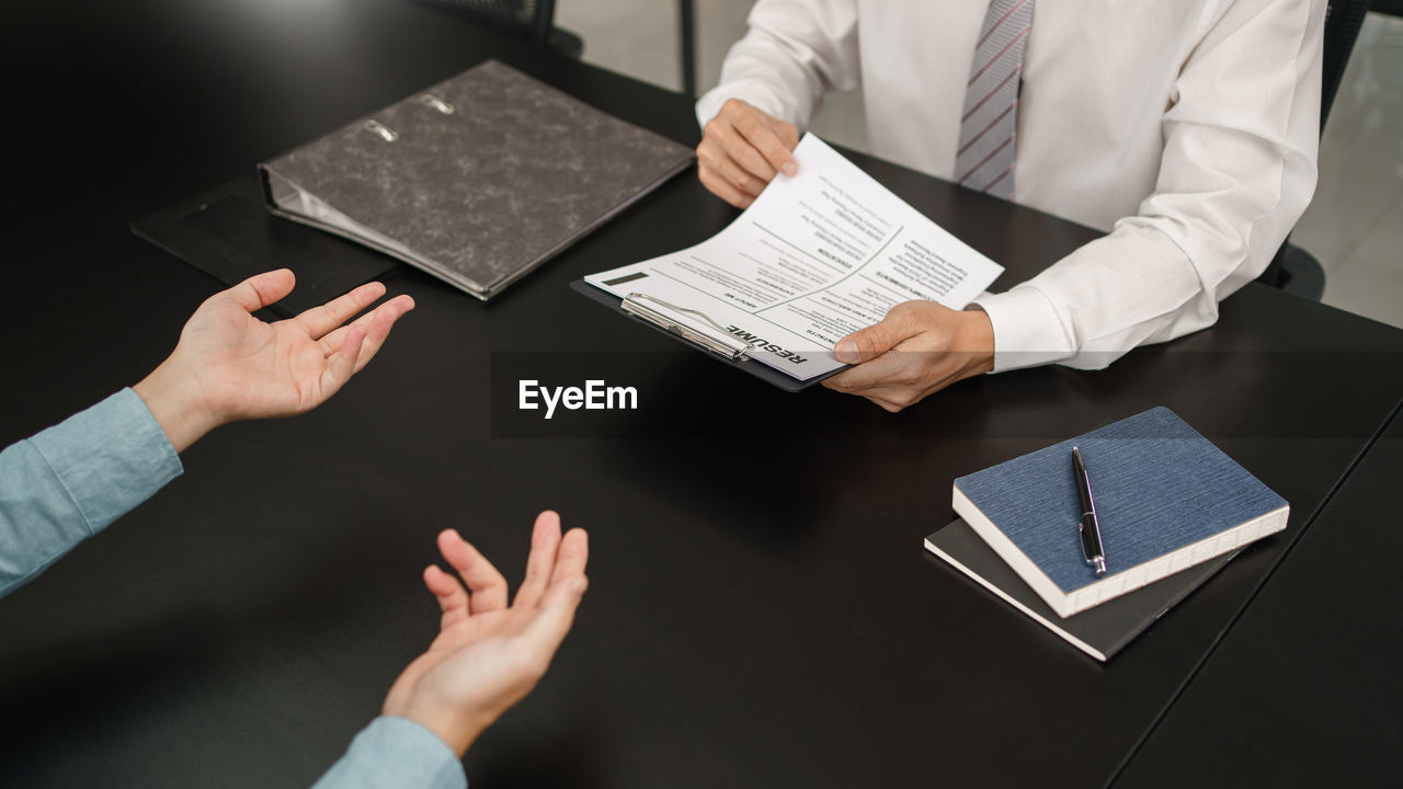 midsection of man holding digital tablet while standing in office