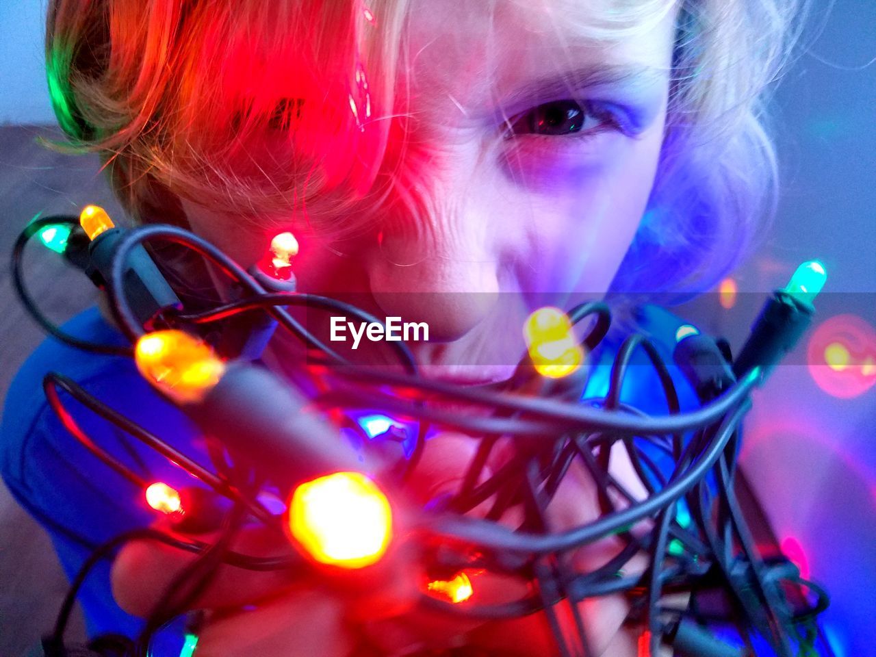 Close-up of boy playing with illuminated string lights at home