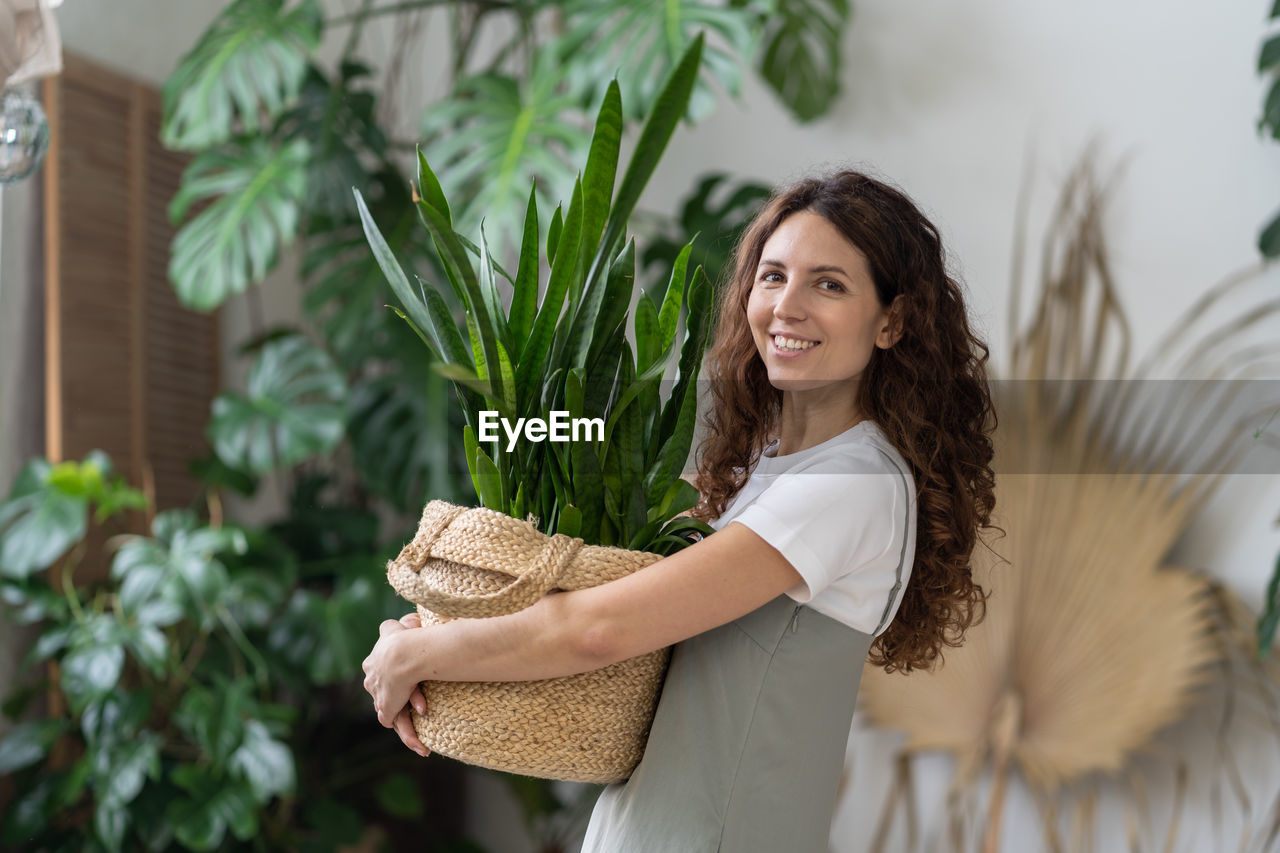 Love for plants. happy woman hold pot with sansevieria houseplant smiling in indoor garden at home