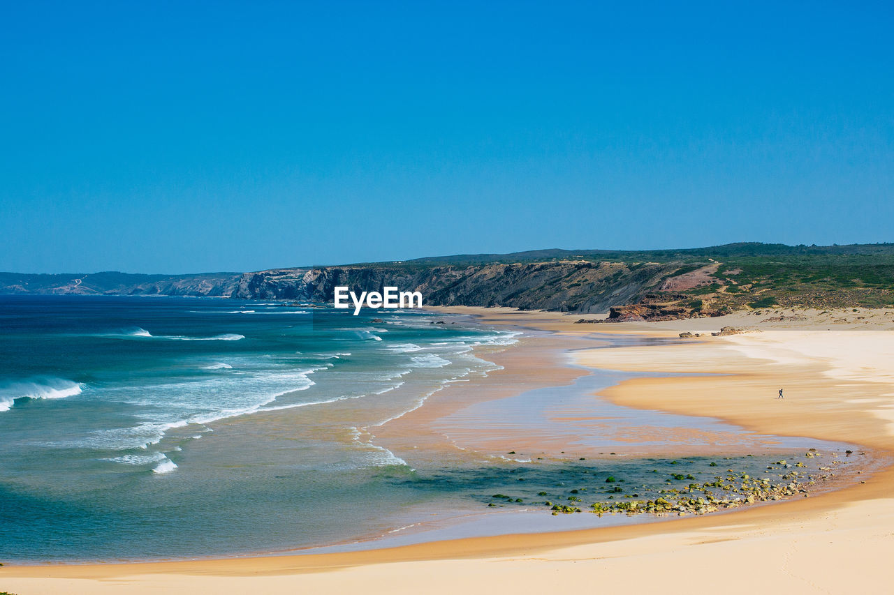 Scenic view of beach against clear blue sky