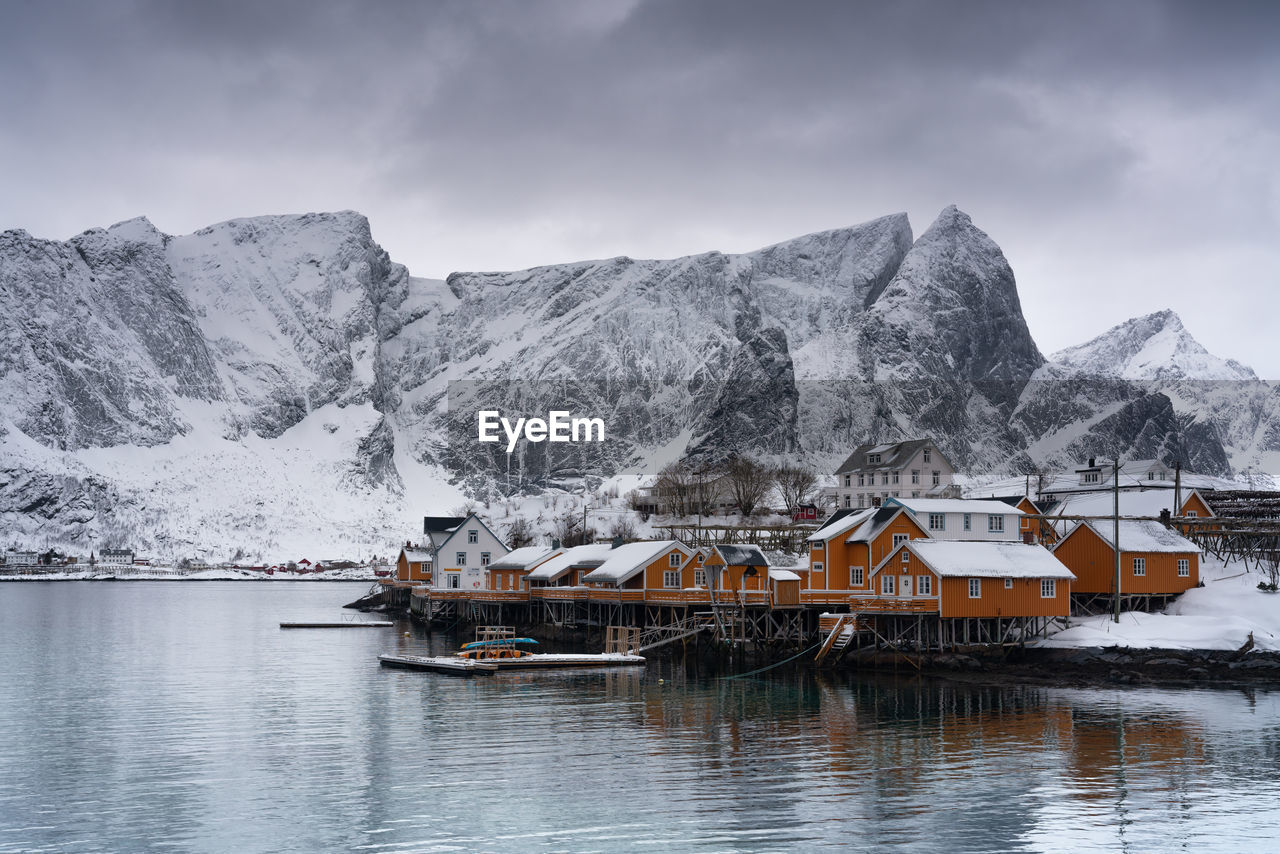 HOUSES BY SNOWCAPPED MOUNTAINS AGAINST SKY