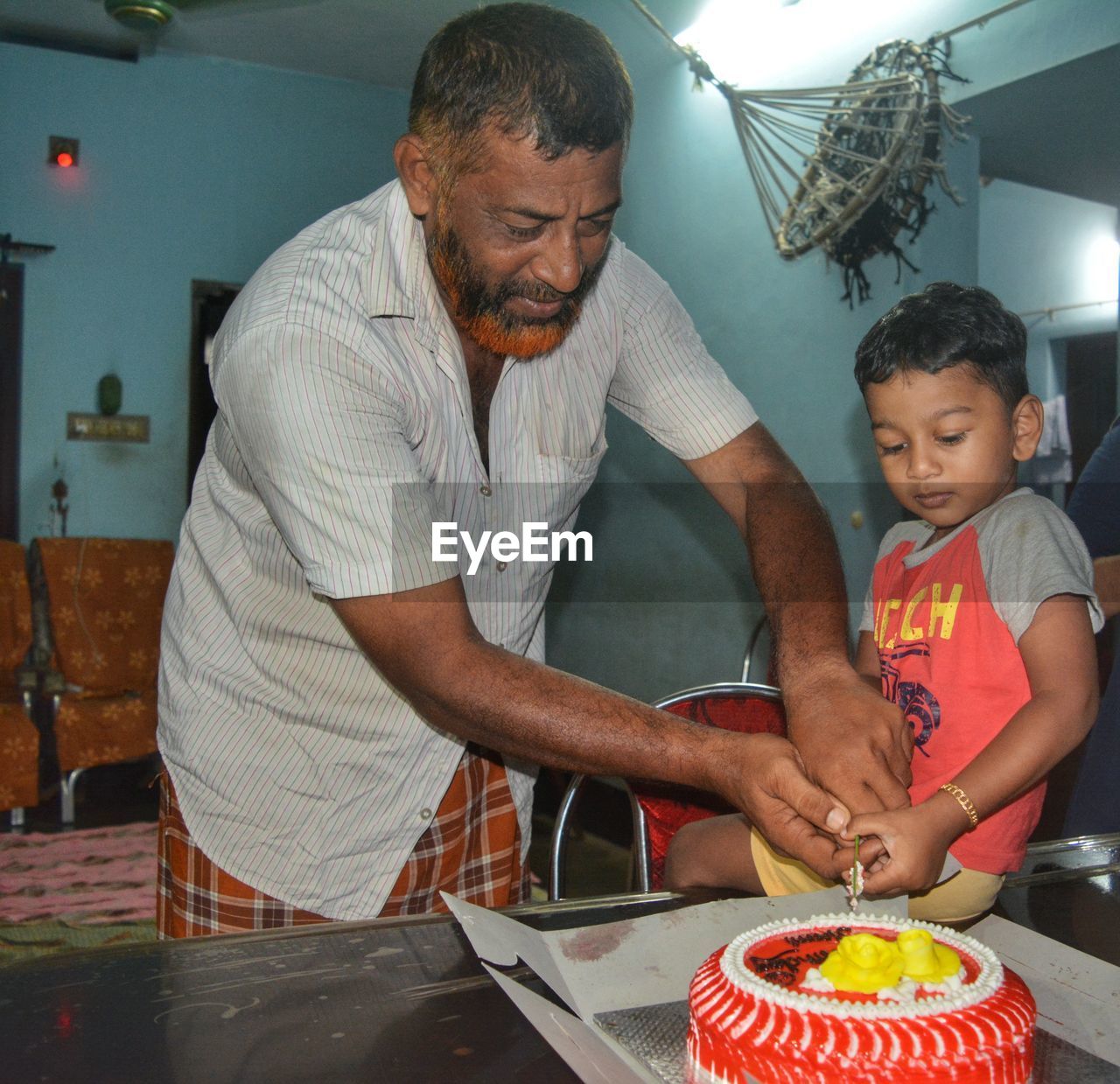 Grandfather cutting cake with grandson at home