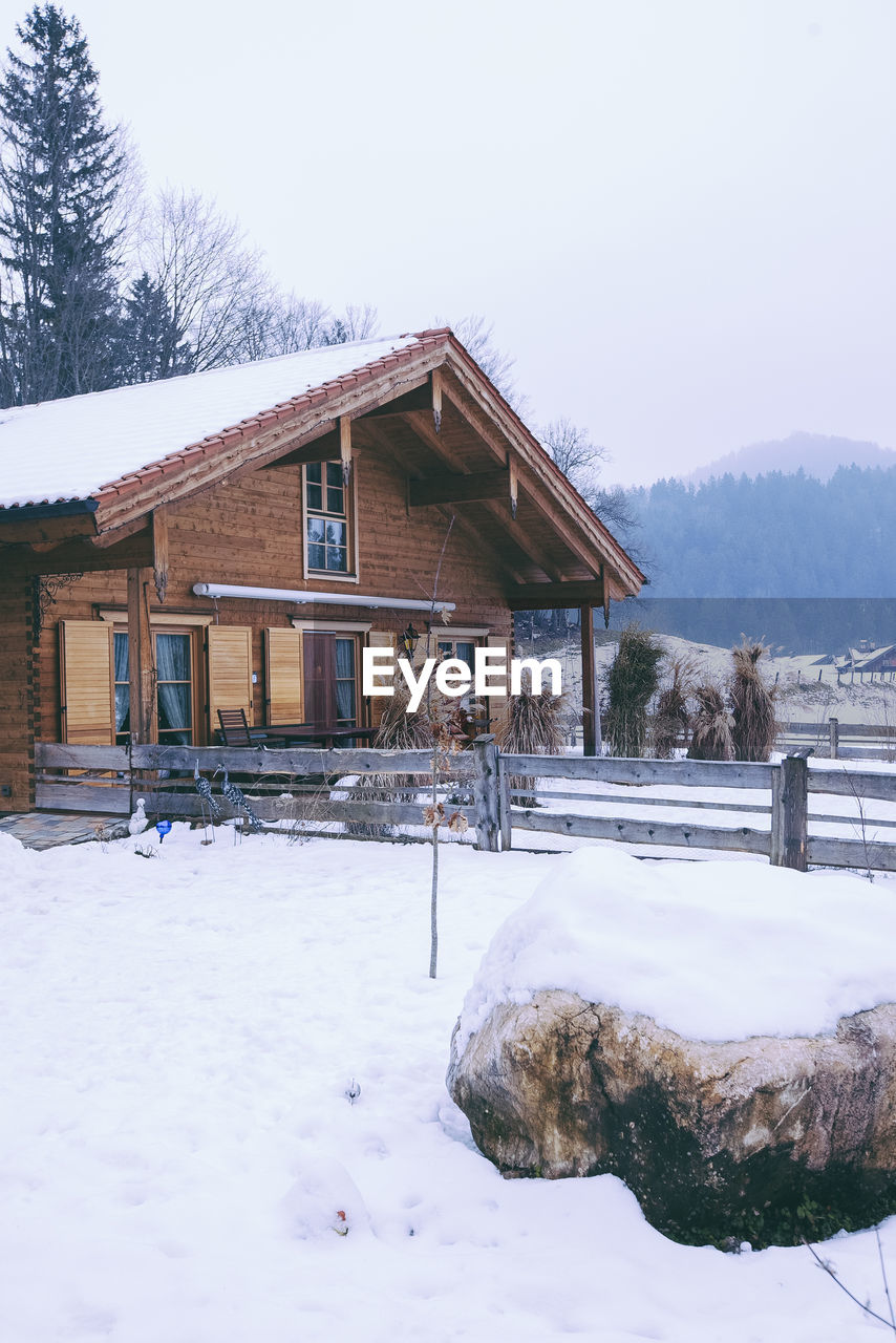 House on snow covered field against sky