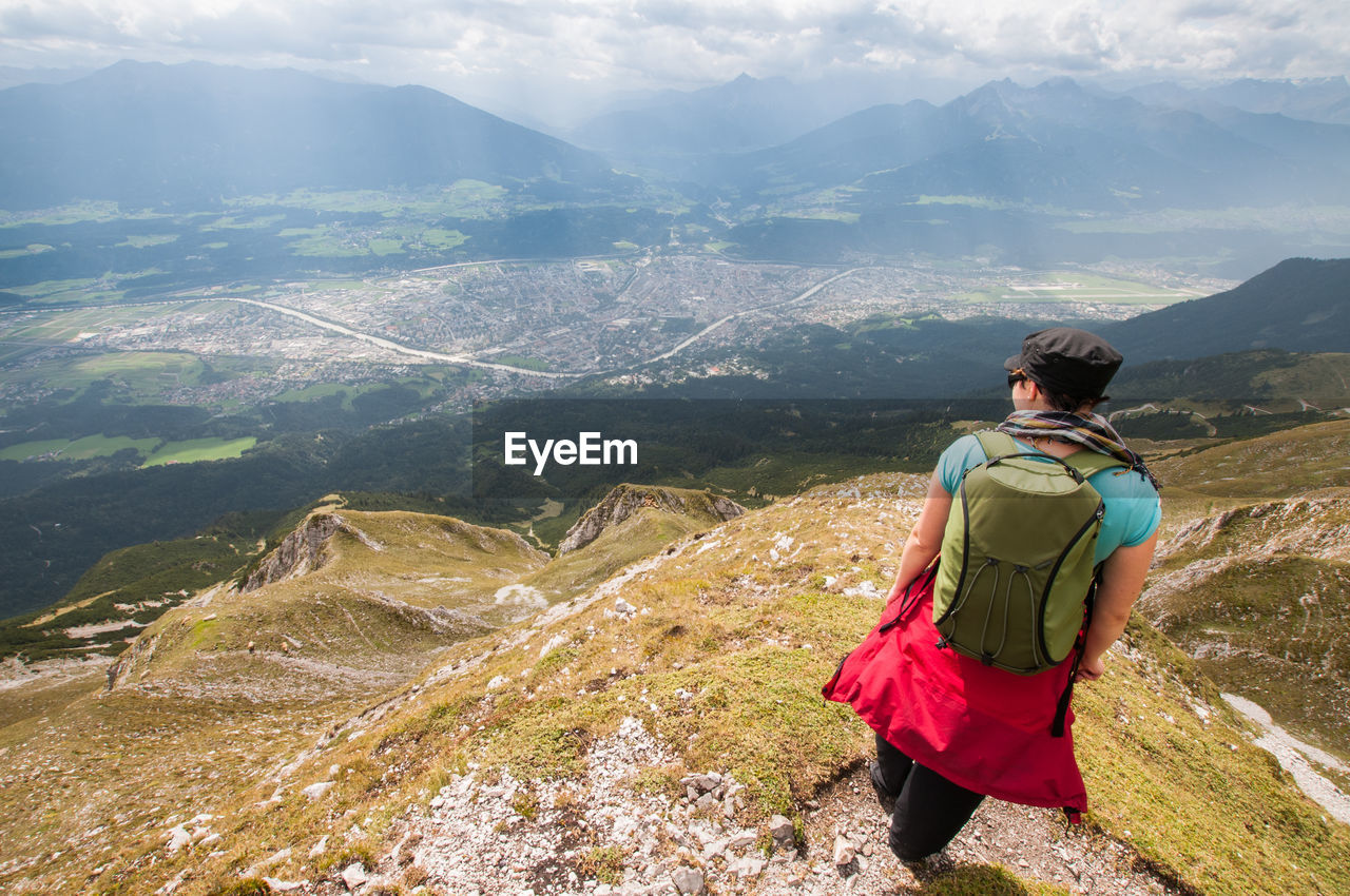 Rear view of female hiker with backpack standing on mountain