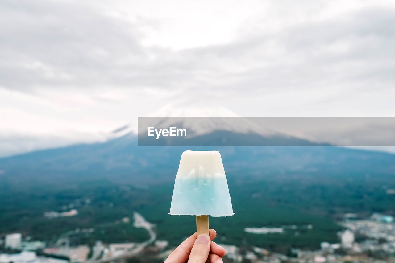 Person holding ice cream against mountain