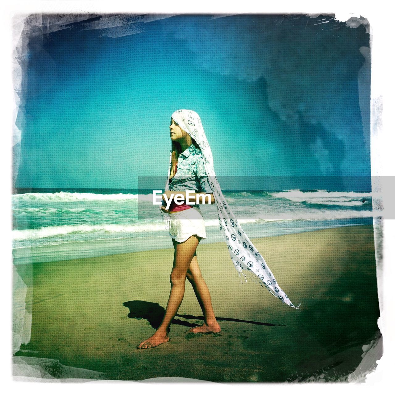 Full length side view of girl with bandana walking on beach against sky